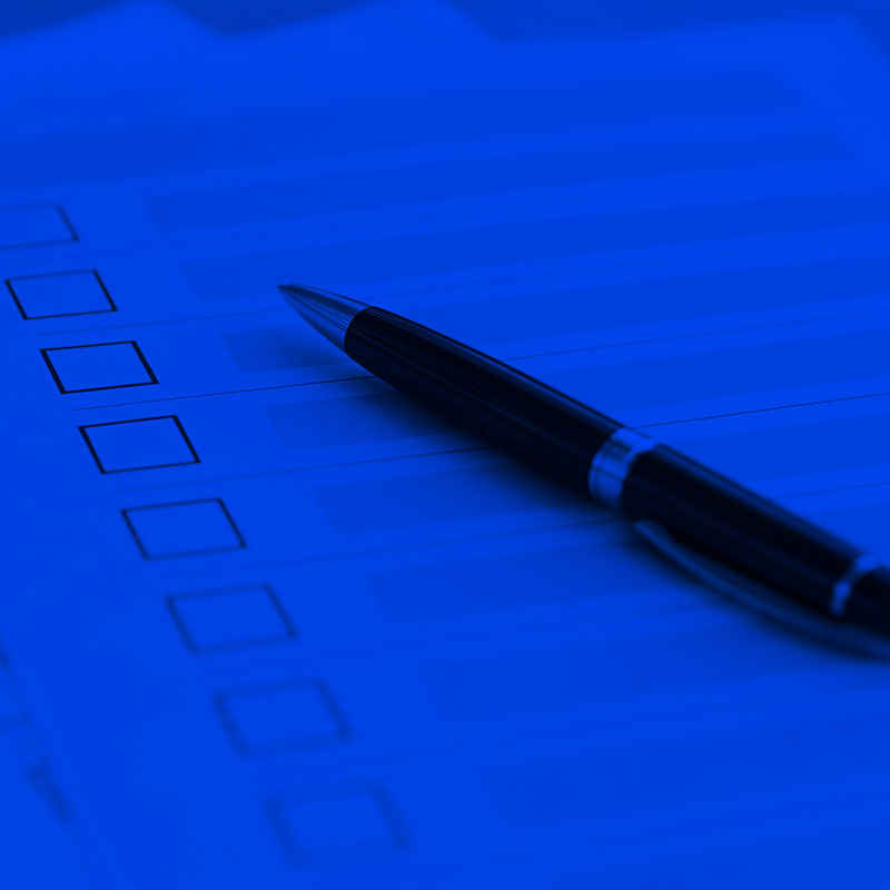 A deep ocean blue image of a black pen laid across a checklist.